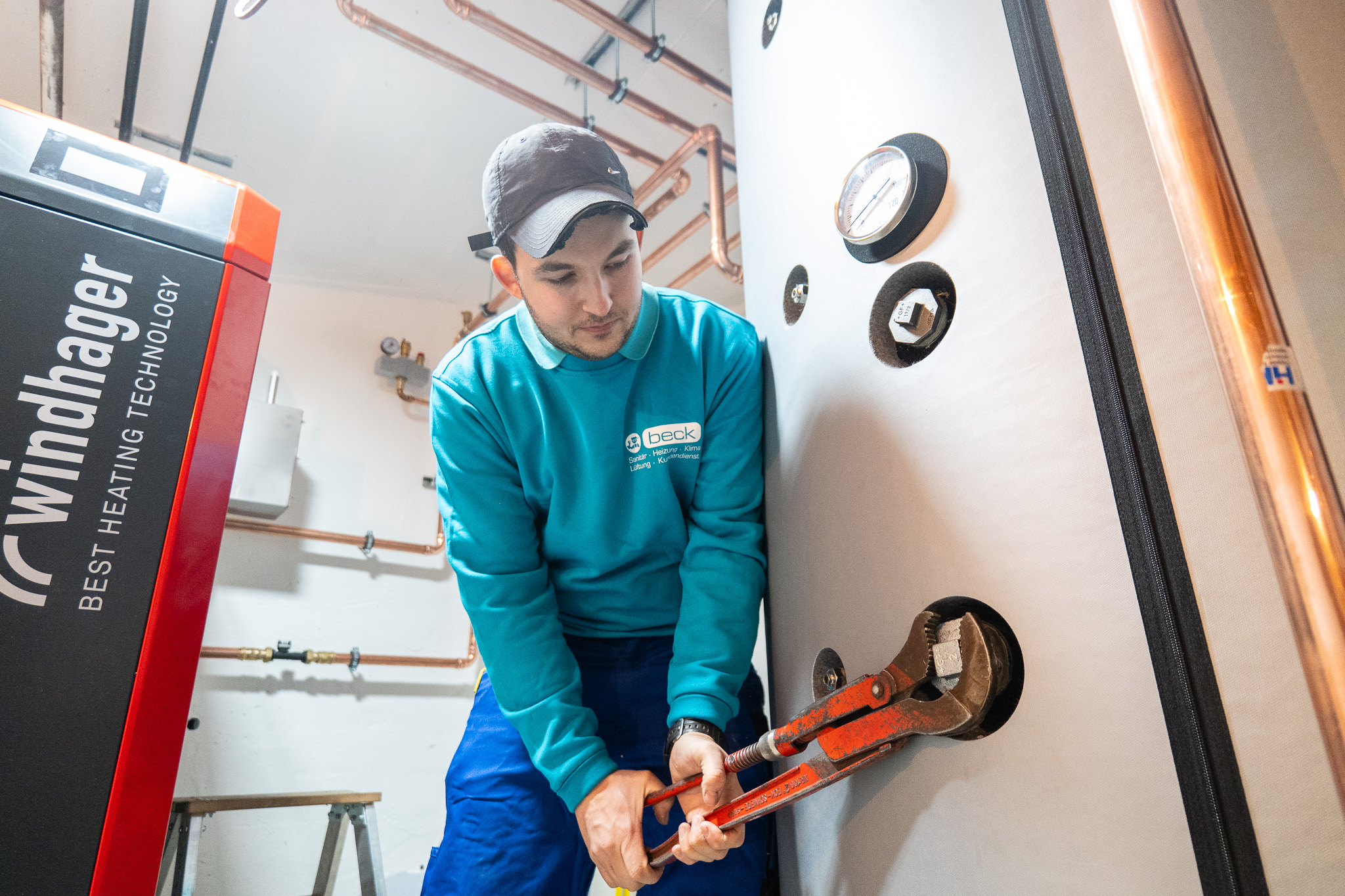 Beck-Mitarbeiter arbeitet mit einem Rohrschlüssel an einem Heizungsspeicher
